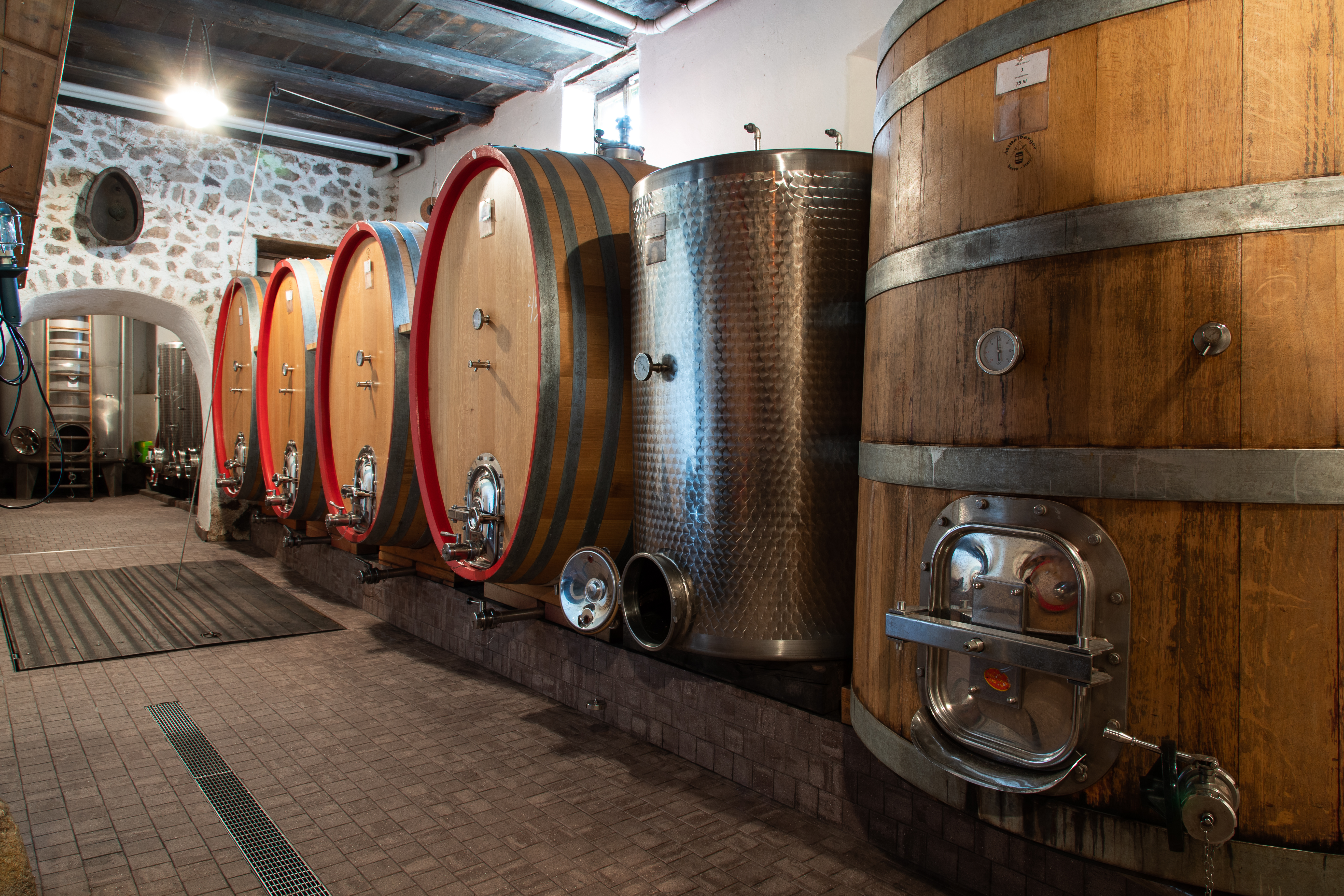 Botti di legno e serbatoio in acciaio nella cantina del Pfannenstielhof con volta in pietra